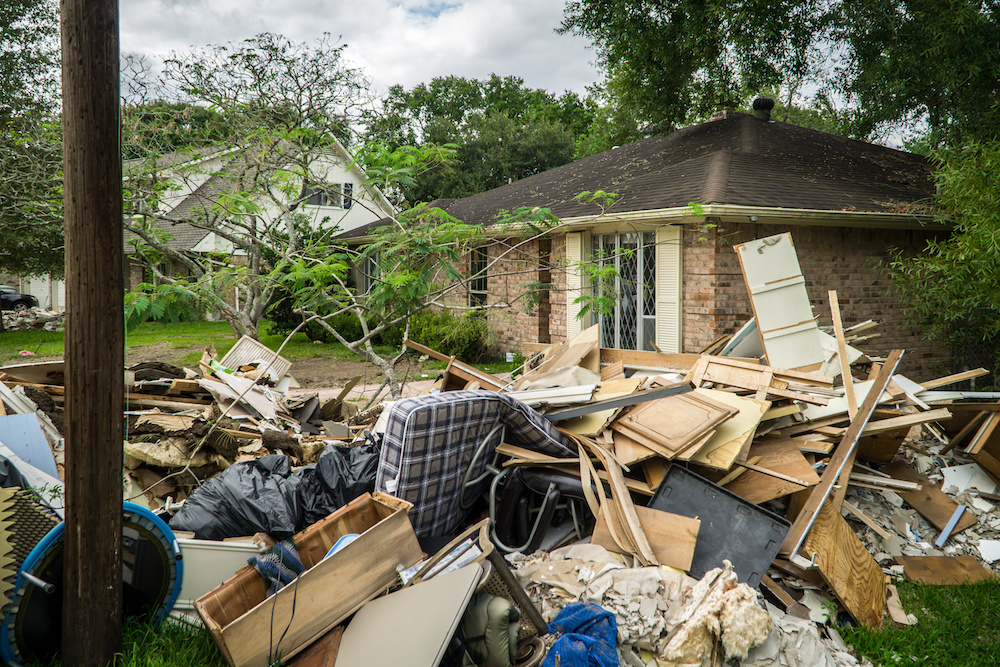 storm damaged house with debris, insurance claim after a hurricane